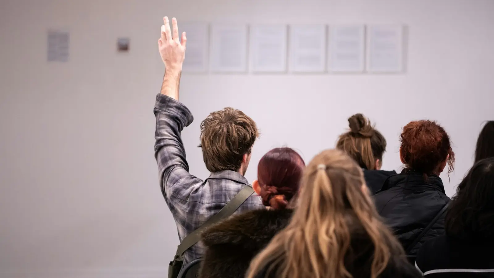 Person raising a hand to ask a question during a public discussion